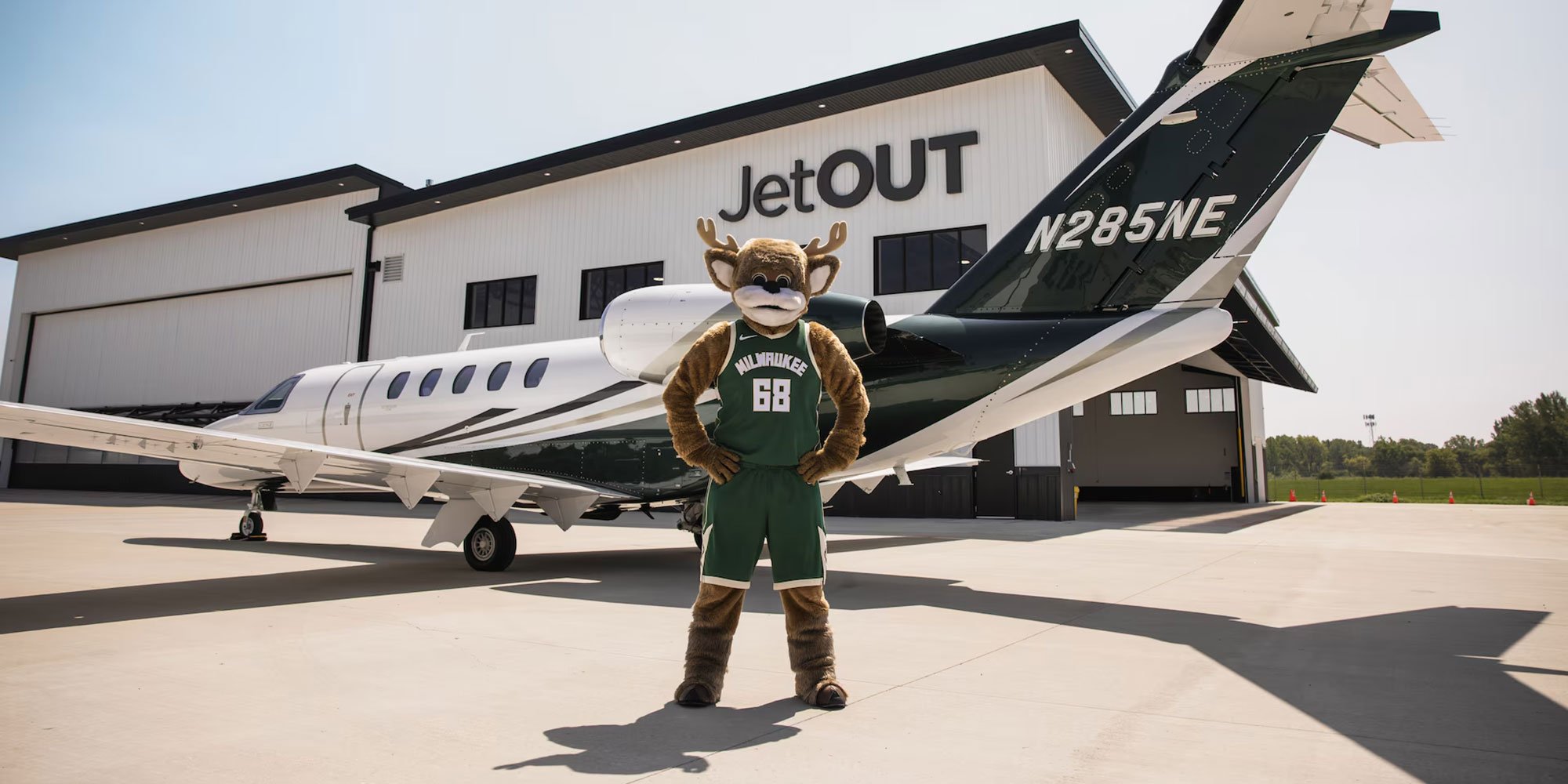 Milwaukee Bucks mascot Bango standing in front of a Jet OUT private jet