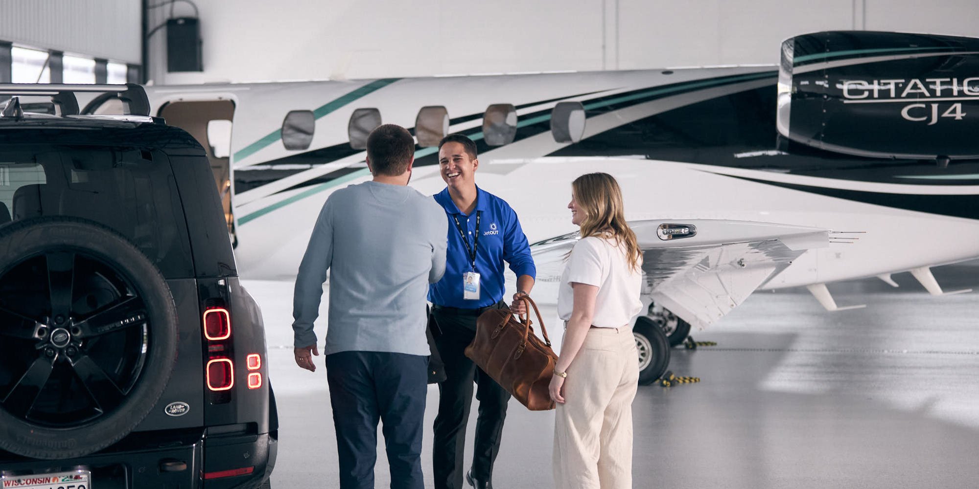Jet OUT staff member greeting clients beside a Citation CJ4 jet in the hangar