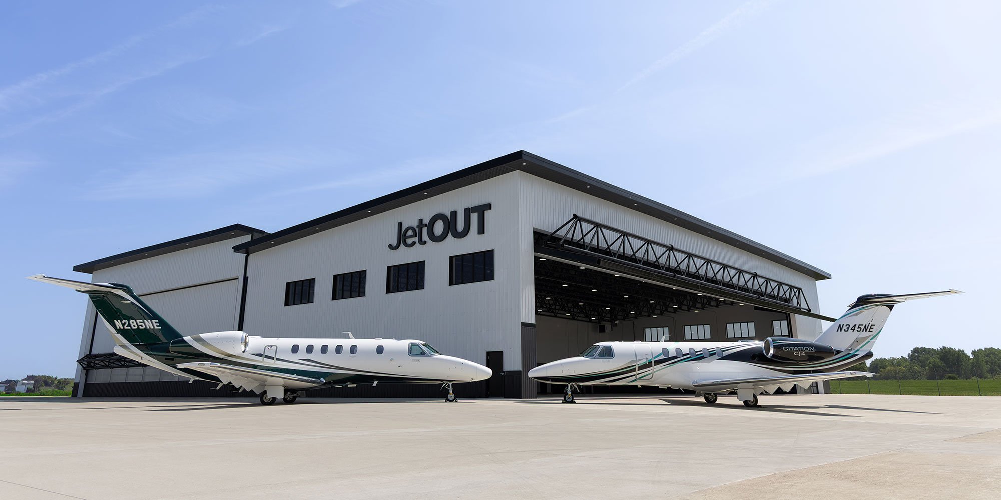 Two Jet OUT private jets parked outside the company's hangar on a sunny tarmac