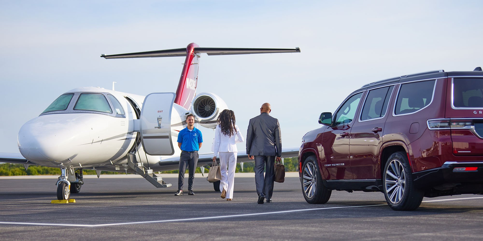 Jet OUT staff member escorting passengers from a private jet to a waiting SUV on the tarmac
